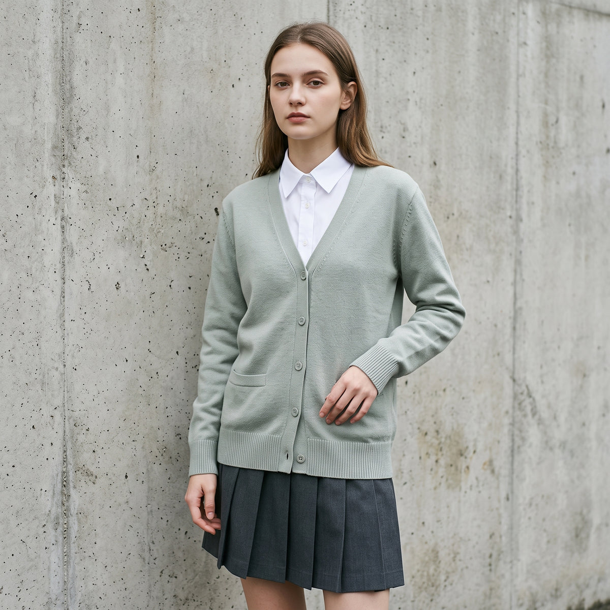 Woman wearing the sage green Japanese school uniform cardigan with white shirt and pleated skirt
