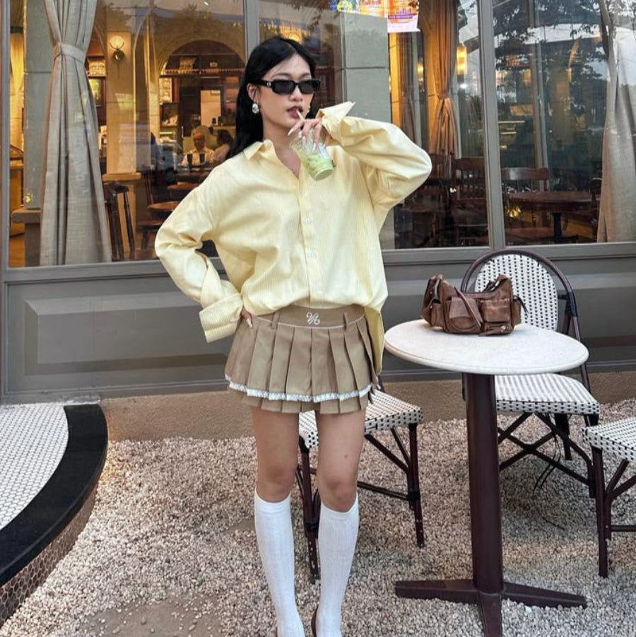 woman wearing light yellow preppy shirt with white skirt