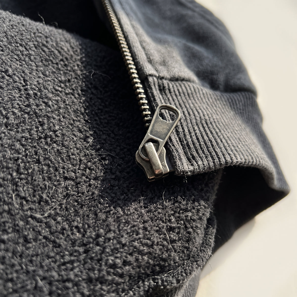 Detail of the washed black fleece, ribbed cuff and zip pull