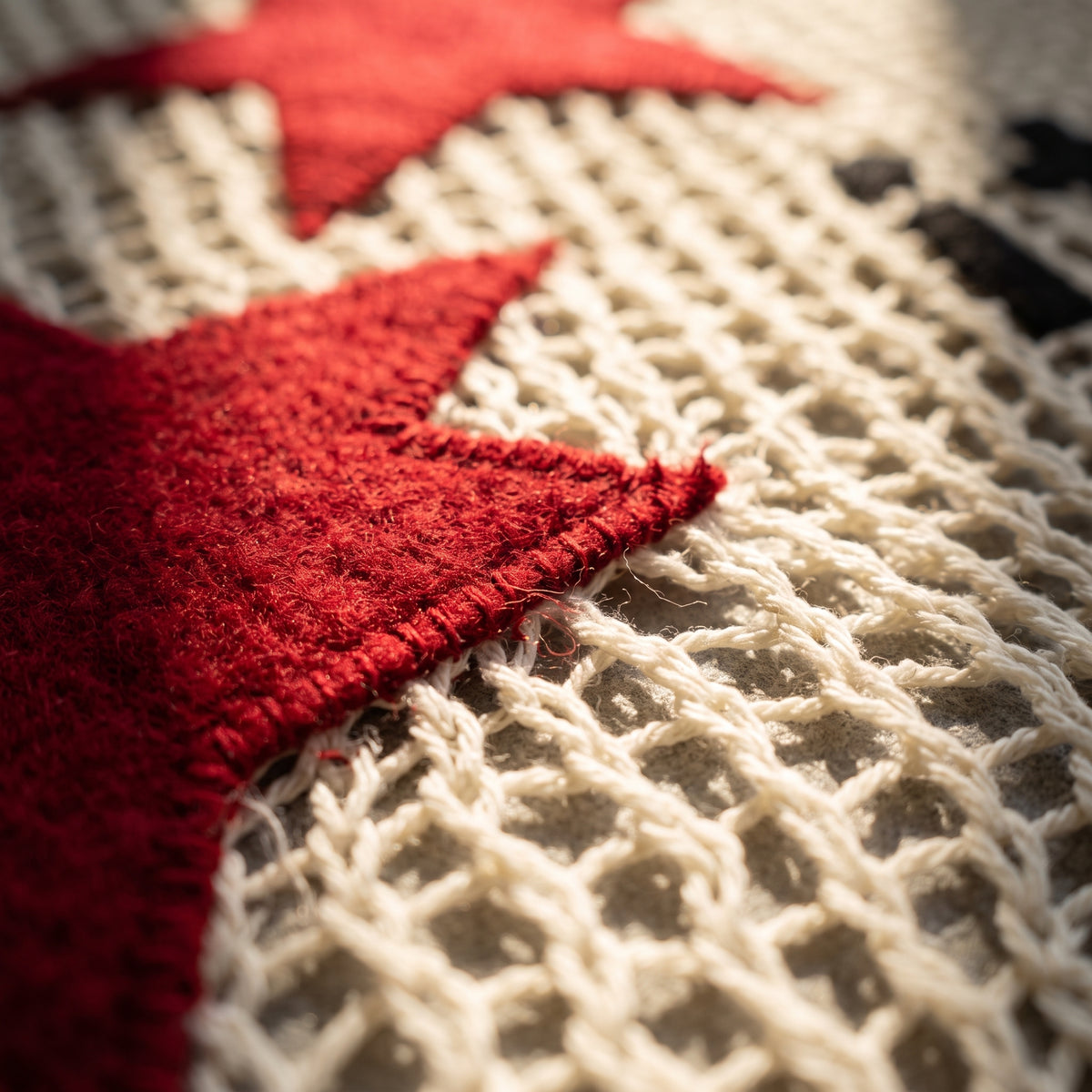 Detail of the red star applique on the cream open-knit fabric