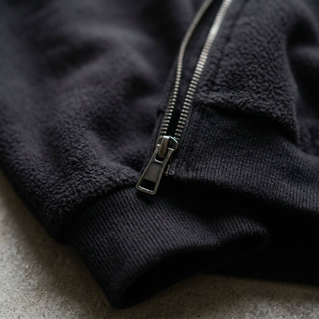 Detail of the black fleece, ribbed cuff and metal zip of the War for Khaus hoodie